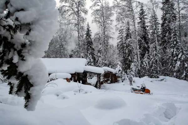 在白雪覆盖的西伯利亚针叶林中猎取冬季住所 冬夜猎人和雪地摩托在森林里的营地里 — 图库照片