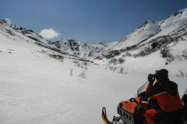 Kar Aracındaki Bir Avcı Dağ Yamacını Dürbünle Inceliyor Kırmızı Tulumlu — Stok fotoğraf