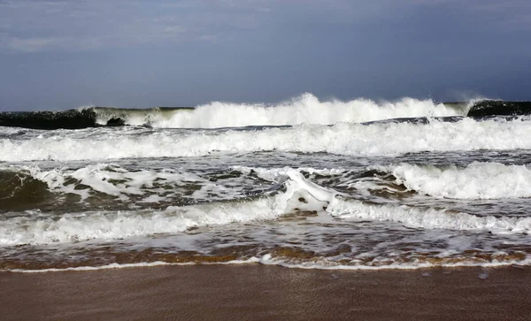 Ocean waves during a storm on a sandy beach. Sea water in spray, foam and waves of storm surf.