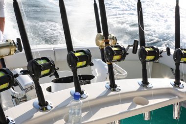 Spinning rods with reels installed in holders before fishing on a boat. Equipment for sea trophy fishing on a fishing yacht. clipart