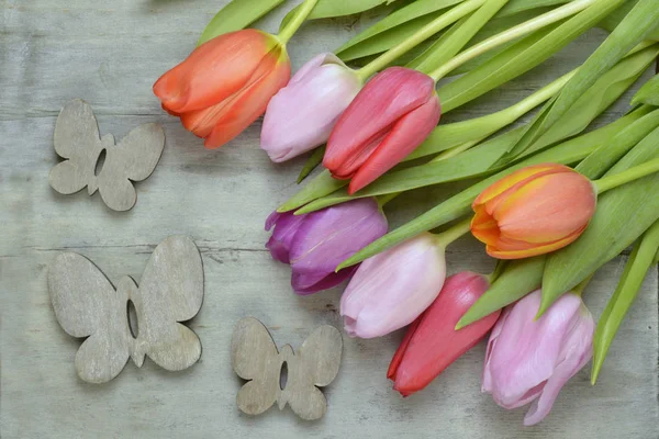 Fond en bois gris vide avec des tulipes printanières fraîches et colorées. Tulipes orange, rouge, rose et violette . — Photo