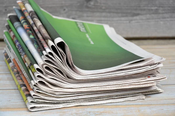 Stacked and piled up newspapers on a wooden table background — Stock Photo, Image