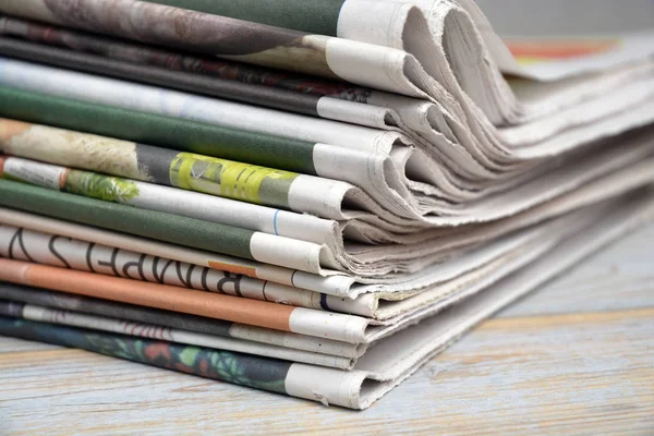 Stacked and piled up newspapers on a wooden table background — Stock Photo, Image