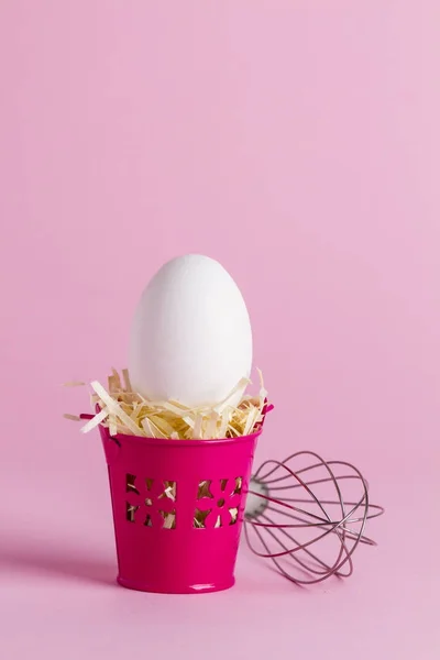 Huevo en un cubo rosado con un batidor —  Fotos de Stock