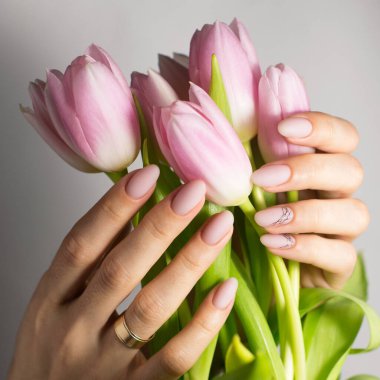 Tırnak cilası. Modern tarz pembe tırnak cilası. Renkli beyaz süt tırnakları. Klasik gelin tırnağı tasarımı. Moda moda kadın manikürü. Güzel, genç bir kadın eli. Kadın akışı tutar