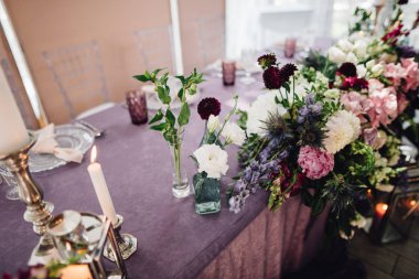 Menekşe bezle masada çiçekler, mumlar ve zengin sofra ile şenlikli dekorasyon
