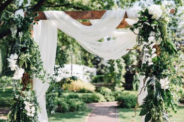 Düğün töreni için kumaş ve beyaz çiçekli şenlikli bir şekilde dekore edilmiş kemer önden görünümü