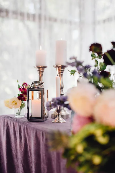 Closeup of festive flowers and candles on table with violet cloth