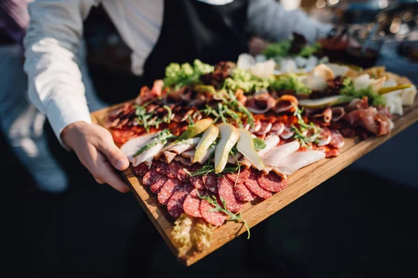 Servitören Bär Träbricka Med Skivat Kött Och Grönska — Stockfoto