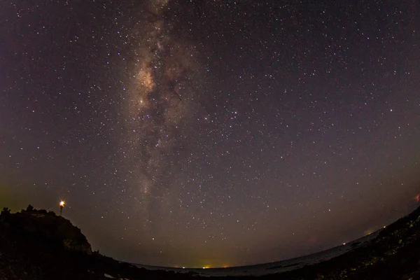 Milky way with lighthouse on the sea background