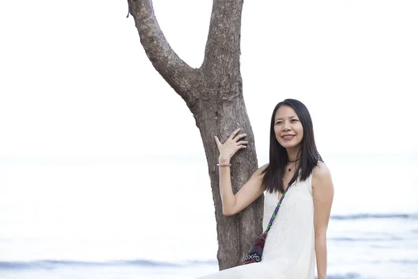 Beautiful asia woman on tropical beach. Portrait of happy young woman smiling at sea on vacation with the sun and sea behind her