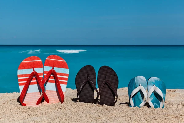 Slippers op het zand strand met blauwe zee en hemel achtergrond — Stockfoto