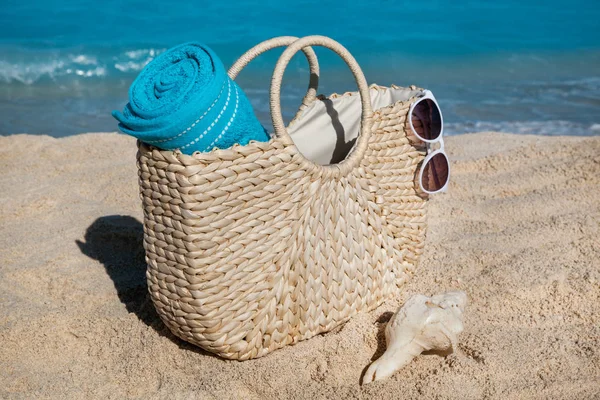 Strooien tas met blauwe handdoek en zonnebril op tropische zandstrand — Stockfoto