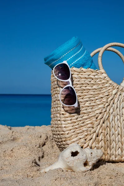 Close-up van zomer strooien tas met blauwe handdoek en zonnebril op een — Stockfoto
