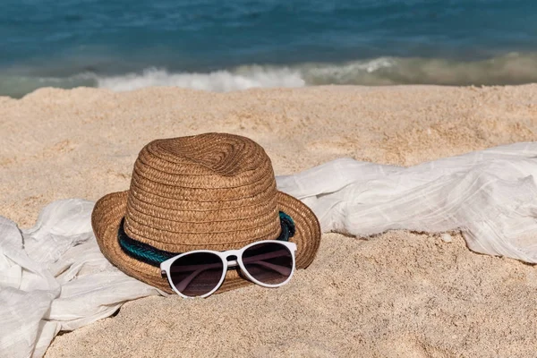 Stro hoed op het zandstrand met witte sjaal en zonnebril — Stockfoto