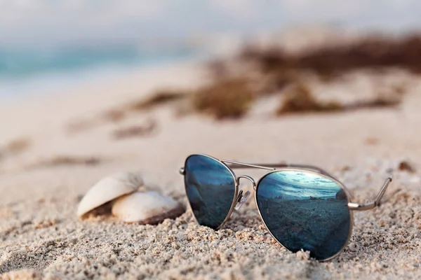 Close-up van blauwe zonnebril op het tropische strand — Stockfoto