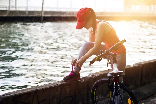 Ciclista donna legatura shoeslace lungo il canale in tramonto sfondo — Foto Stock