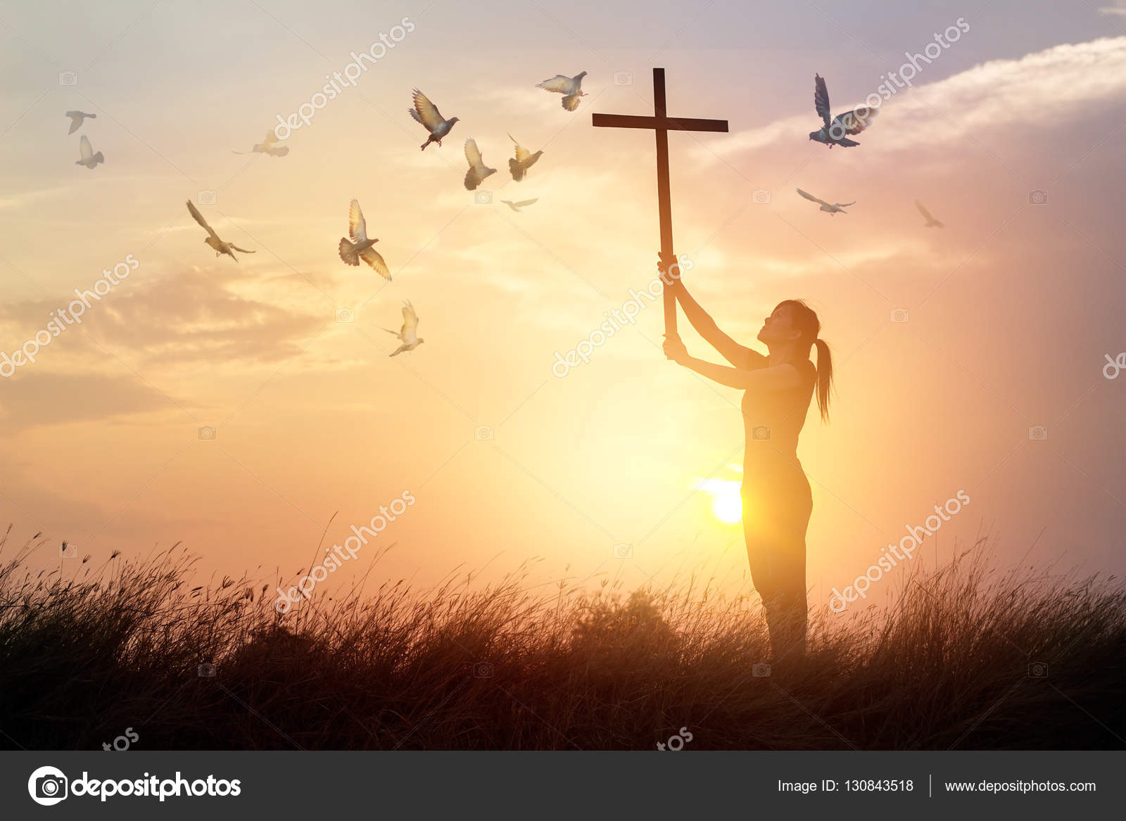Woman praying with cross and flying bird in nature sunset