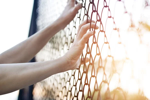 Woman hands touching a metal wire fence — Stok fotoğraf