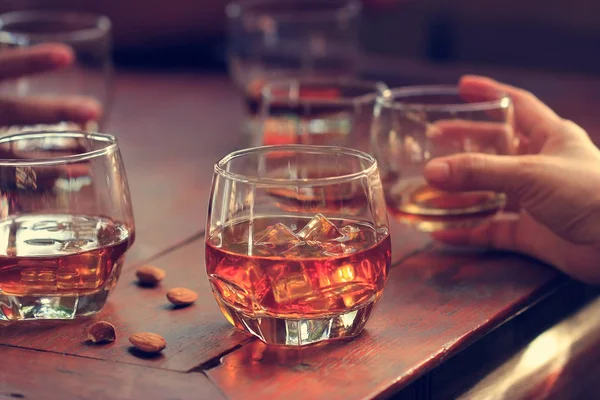 Whiskey bourbon in a glasses with ice on wooden table background