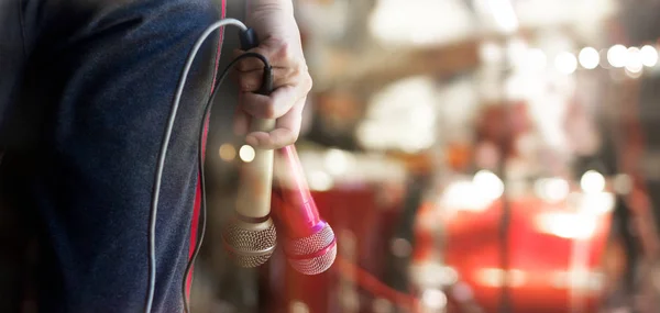 Man holding microphones in hand on concert stage background — Stock Photo, Image