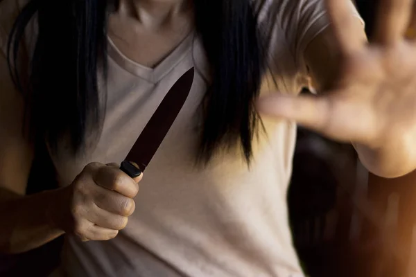 Žena držící nůž v ruce zároveň brání před útokem. — Stock fotografie