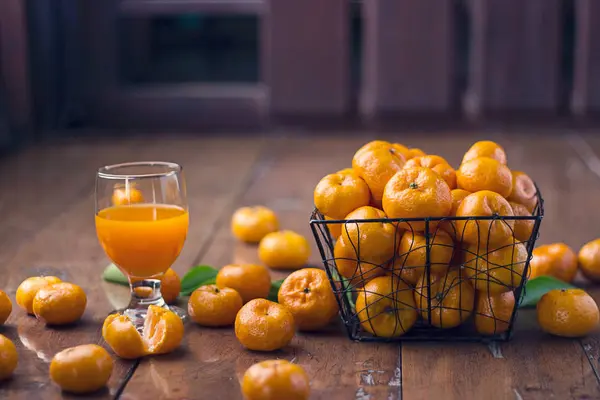 Orangen Früchte im Korb und ein Glas Orangensaft auf Holzrücken — Stockfoto