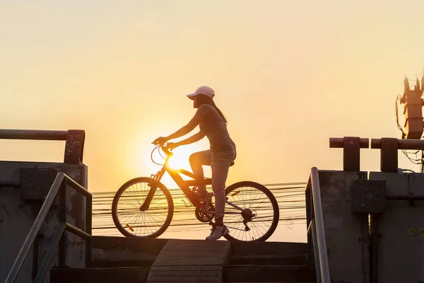 Mujer montando en bicicleta, haciendo ejercicio en la ciudad del atardecer — Foto de Stock