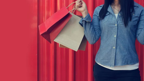 Woman holding shopping bags on red background — Stock Photo, Image