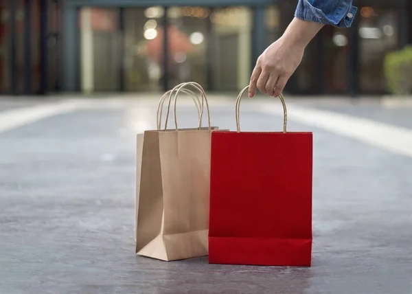 Mano con borse della spesa sul pavimento in sfondo centro commerciale — Foto Stock
