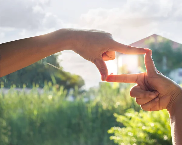 Mãos símbolo com casa em luz do sol natureza fundo — Fotografia de Stock