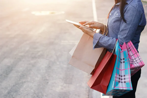 Mulher com sacos de compras, usando smartphone ou tablet — Fotografia de Stock