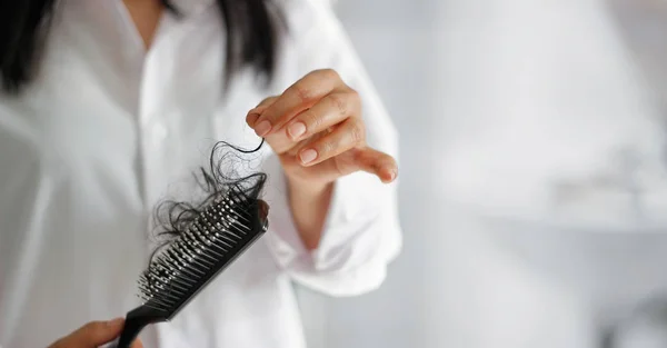 woman losing hair on hairbrush in hand, soft focus