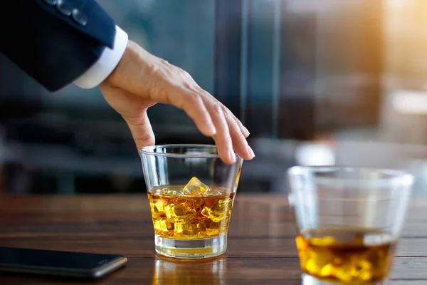 Рука бизнесмена трогает бокал виски — стоковое фото