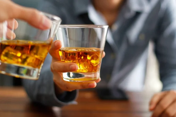 Крупный план двух мужчин, звонящих стаканами виски, пьющих алкогольные напитки — стоковое фото