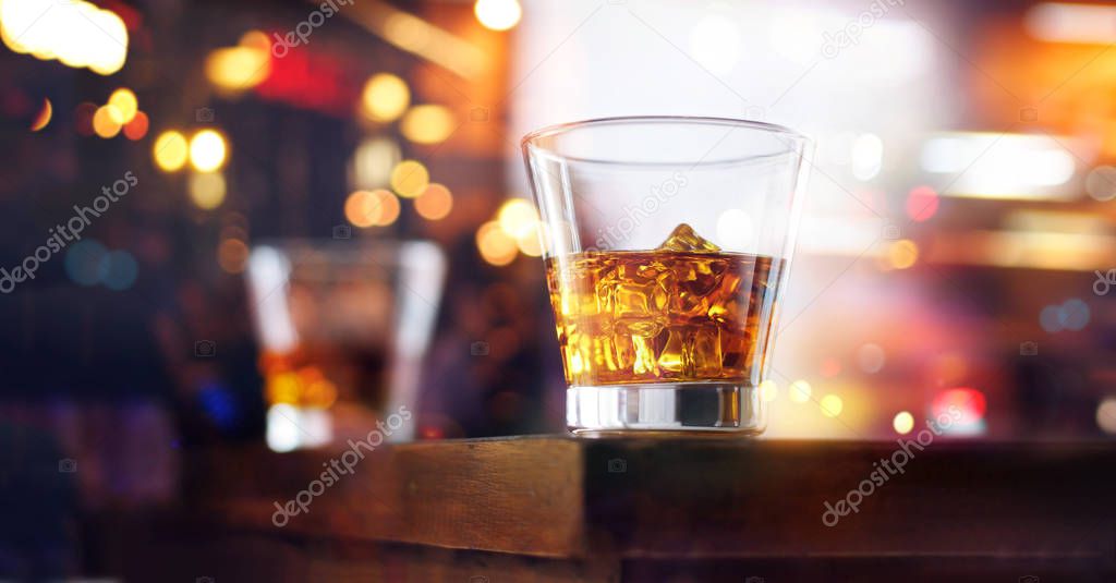 Glass of whiskey drinks with ice cube on table wooden bar