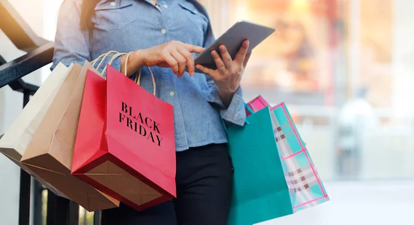 Mulher usando tablet e segurando sacos de compras Black Friday — Fotografia de Stock