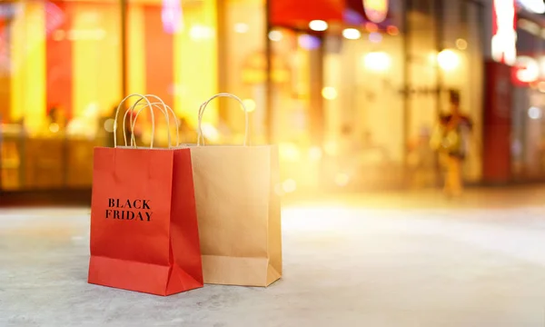 Venerdì nero sacchetti di carta per lo shopping sul pavimento di fronte al negozio centro commerciale di notte — Foto Stock