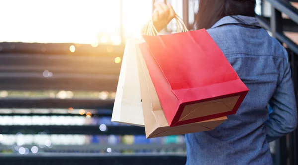 Visão traseira da mulher segurando saco de compras enquanto no andar de cima ao ar livre — Fotografia de Stock