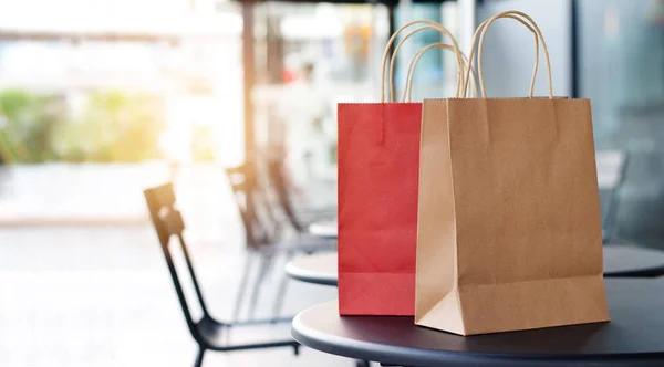 Sacchetti della spesa rossi e marroni sui tavoli davanti al negozio del centro commerciale sfondo — Foto Stock