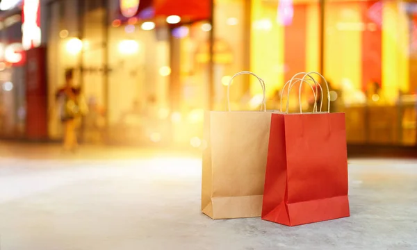 Sacos de compras vermelhos e castanhos na frente do chão da loja do shopping à noite — Fotografia de Stock
