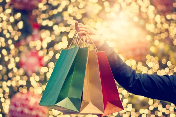 Sacchetti di shopping di Natale in mano sulla decorazione di Natale e ligh — Foto Stock