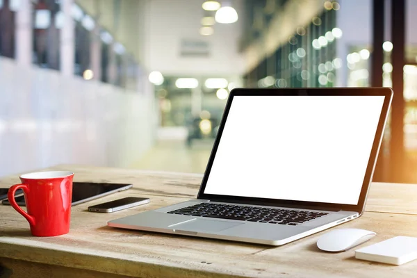 Laptop com tela branca em branco na mesa no fundo do escritório — Fotografia de Stock