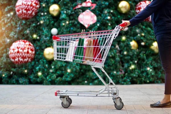 Shopping natalizio - shopper donna con sacchetti di carta nel carrello della spesa — Foto Stock