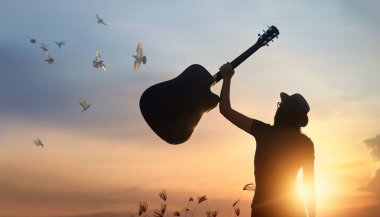 Gitar silueti günbatımı arka plan üzerinde özgür kuşlar ile merkez over yükselterek müzisyen