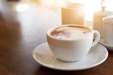 Kahve fincanı ahşap masa arkasında.