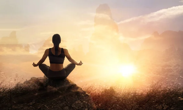 Mujer practica yoga meditando sobre una piedra, fondo de montañas puestas de sol —  Fotos de Stock