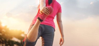 Genç kadın atlet günbatımı kırsal iz çalıştırmadan önce bacaklarını germe Isınma