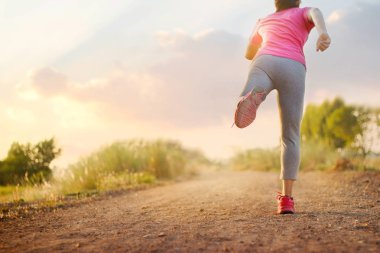 Kadın egzersiz günbatımı arka plan kırsal yol iz üzerinde çalışan. Fitness ve sağlıklı yaşam konsepti. 