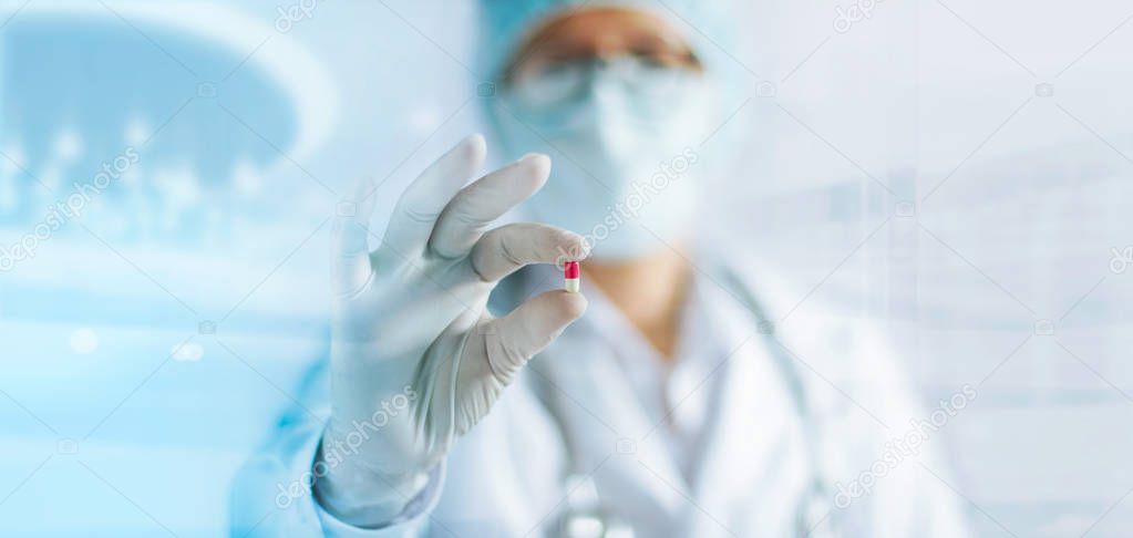 Medicine doctor holding a color capsule pill in hand with white glove in laboratory 